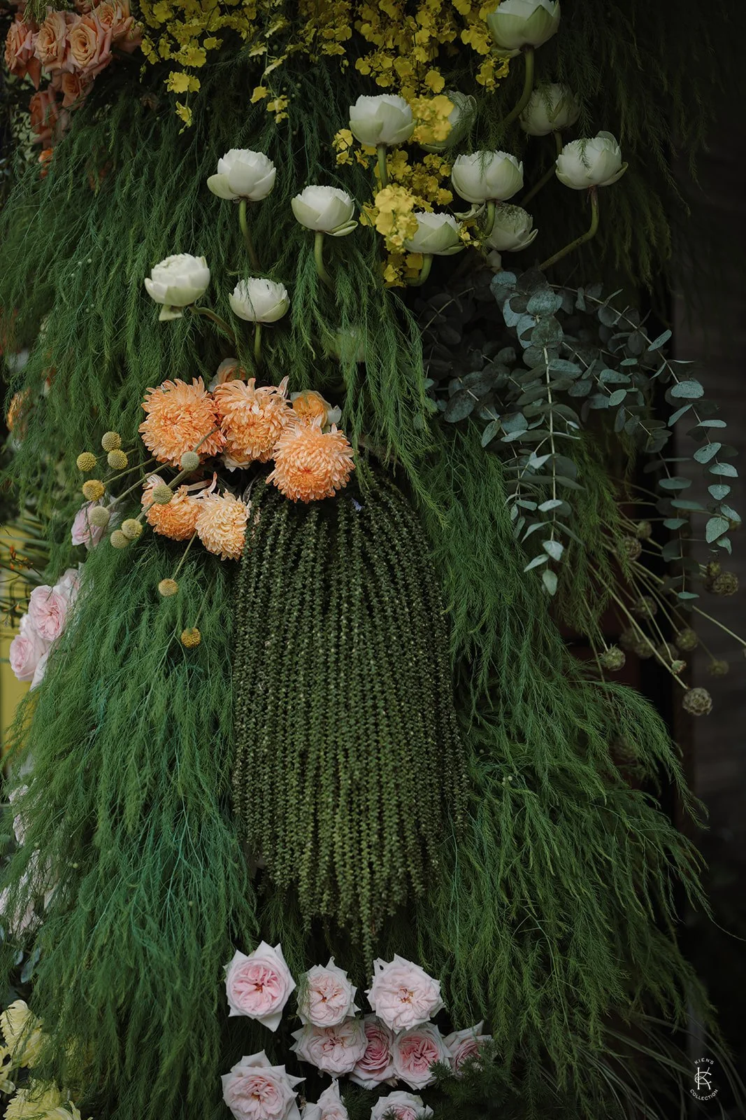 Layered floral installation with sculptural greenery and warm colour